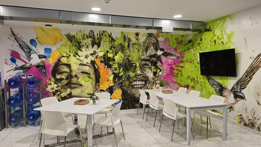 Large-scale abstract portrait mural with birds and vibrant colors in InDrive office space Limassol Cyprus